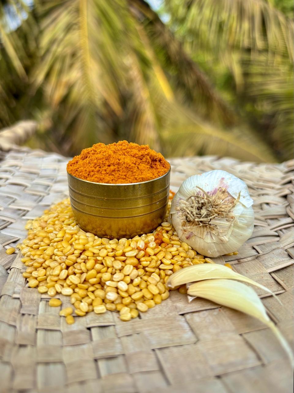 About Us Turmeric, garlic and lentils laid out on a woven mat before grinding