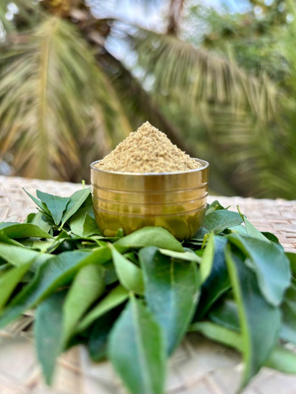 About Us Freshly ground spice powder in a brass bowl on curry leaves